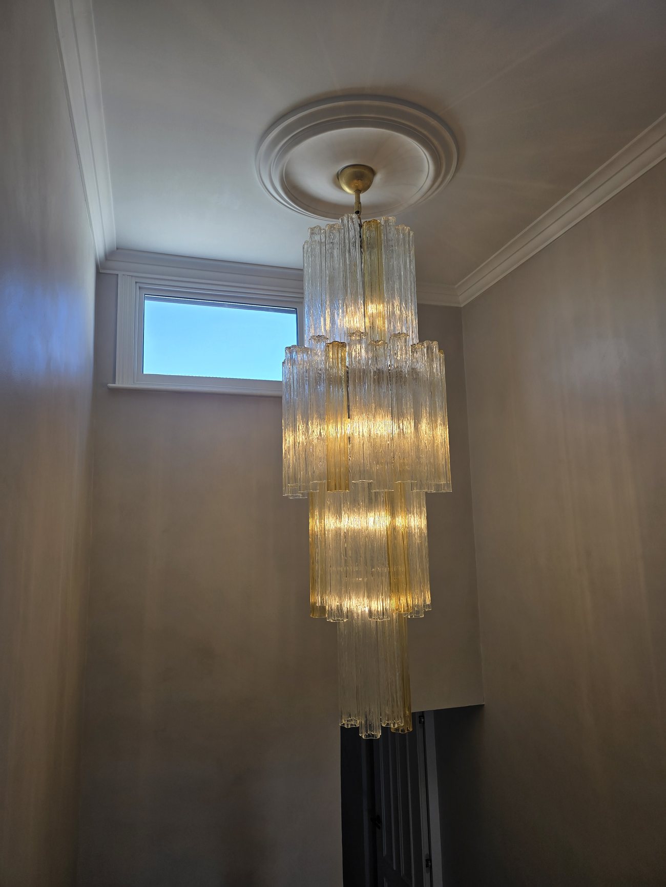 Glass-tube chandelier installed on a ceiling rose